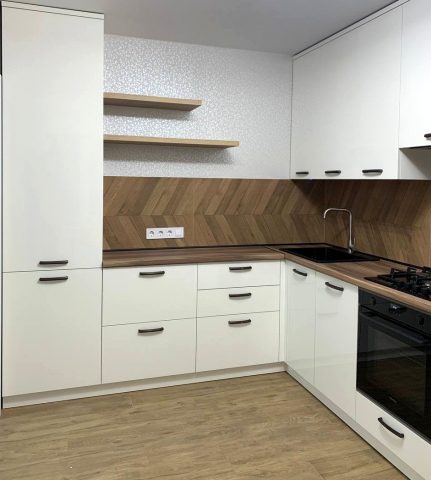 Сучасна кутова кухня з дерев’яним фартуком та вбудованою технікою